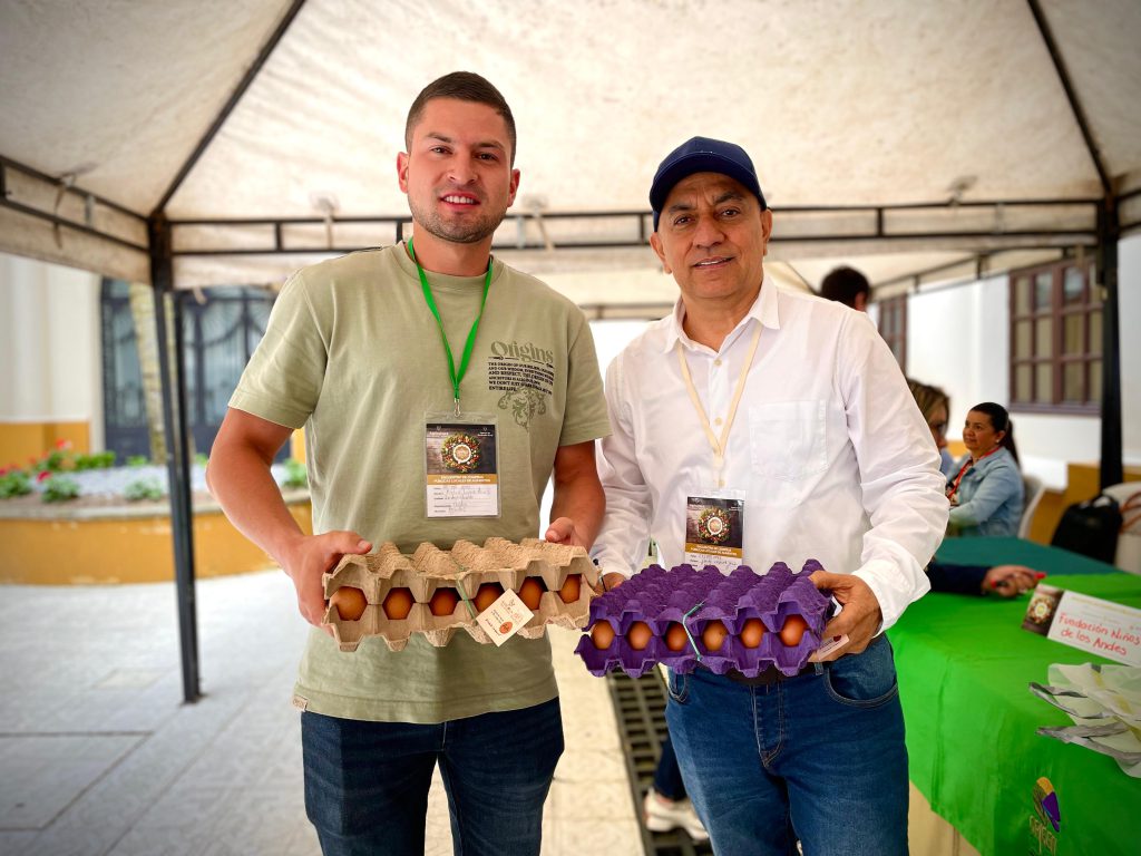 Foto de dos hombres posando para una foto, cada uno sostiene una cubeta que contiene huevos.