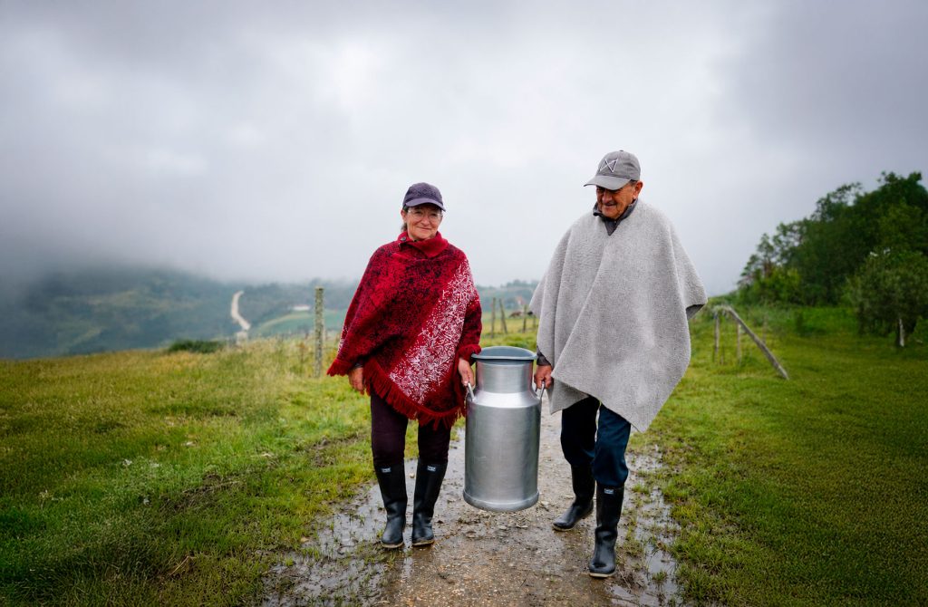 día de la leche 2026 2 campesinos hombre y mujer cargando una cantina de leche grande
